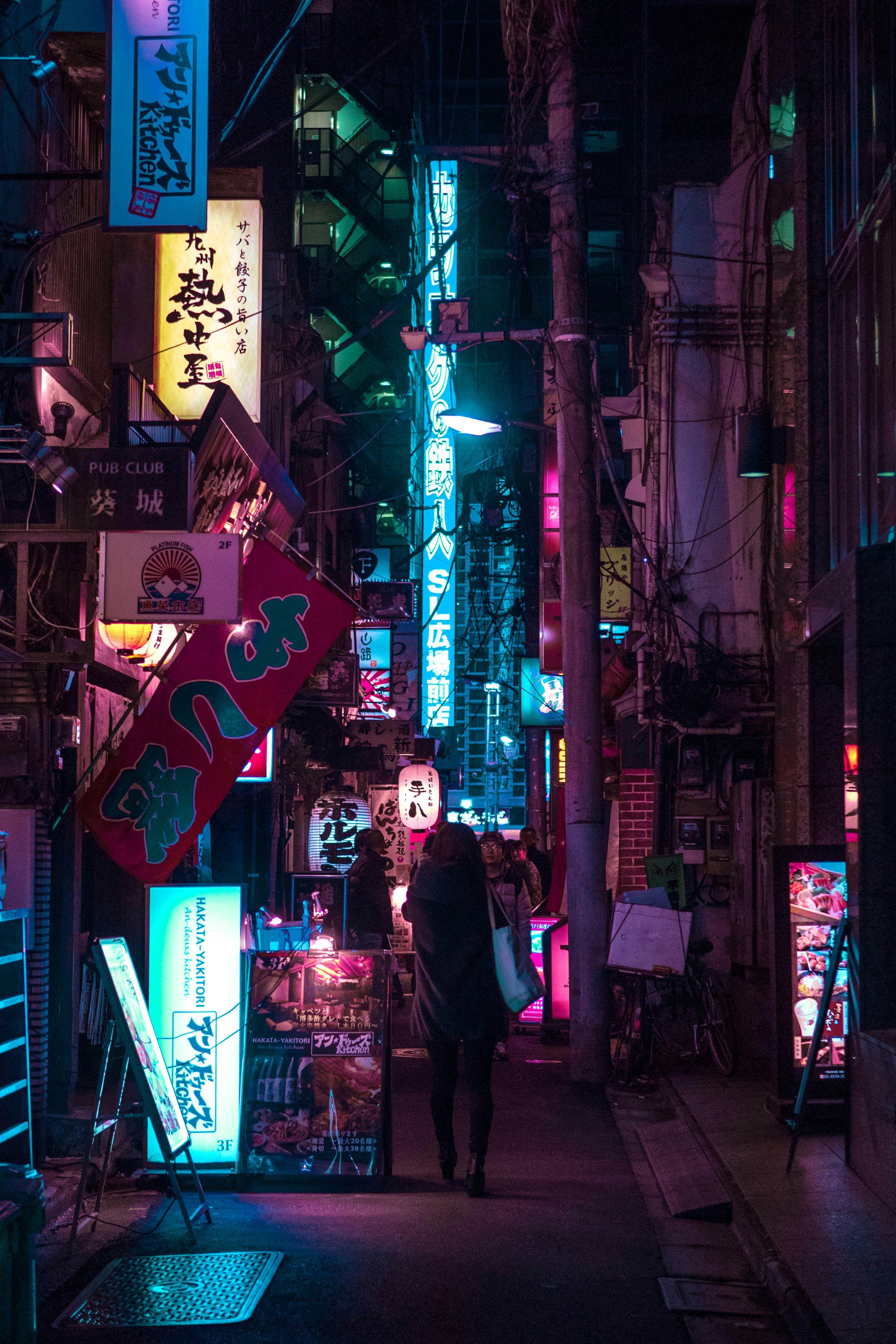 man in black coat standing beside store during night time